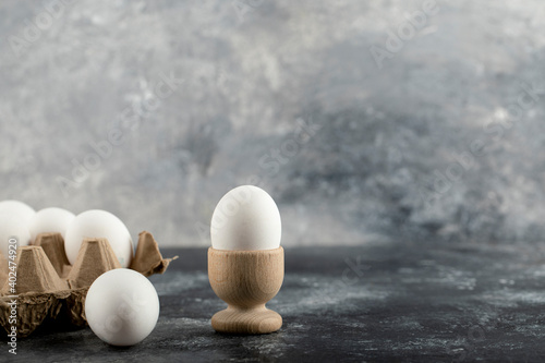 Raw chicken egg in eggcup with eggbox on a marble background photo