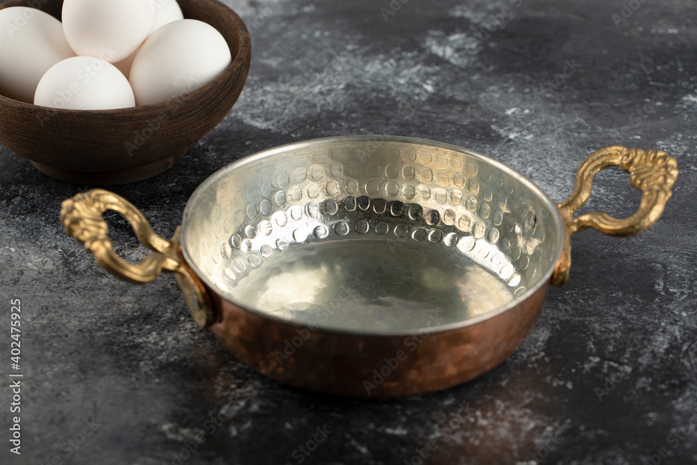 Some of white raw chicken eggs with saucepan