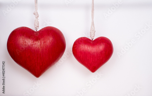 Two red hanging hearts, one big on the left and a smaller one on the right, both on a white background