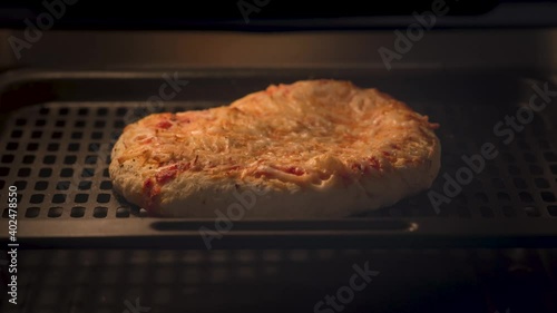 Home made pizza being cooked in an air fryer.  Close up time lapse view of a cheese pizza puffing up and turning golden brown in the oven.