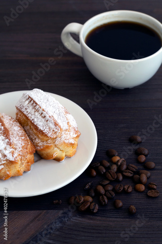 Traditional french tasty dessert on dark background. homemade vanilla eclairs or profiteroles on a wooden table. copy space. cup of black coffee with beans. vertical