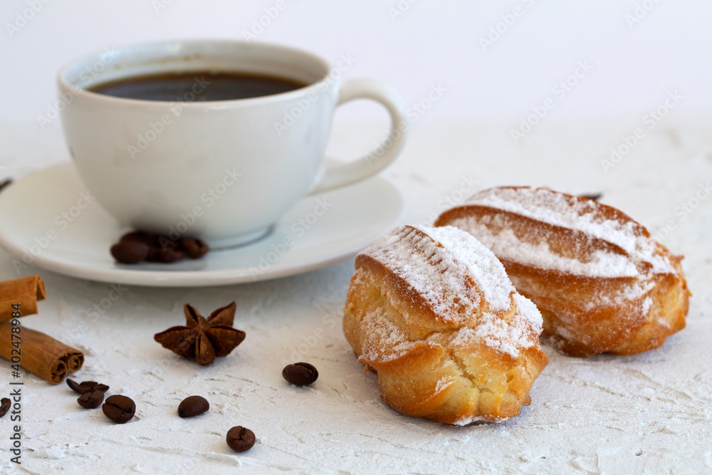 vanilla eclair on a plate on white background. Coffee cup with coffee beans and anise star, cinnamon sticks on white background. Traditional french tasty dessert. copy space vanilla eclair on a plate on white background. Coffee cup with coffee beans and anise star, cinnamon sticks on white background. Traditional french tasty dessert. copy space