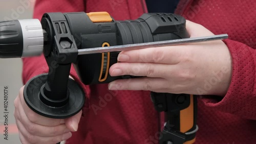 Woman in the store chooses an electric drill. Camera shoots close up showing hands and working tool. Tech. data 4K video, 25 fps, ProRes, 10 bit color