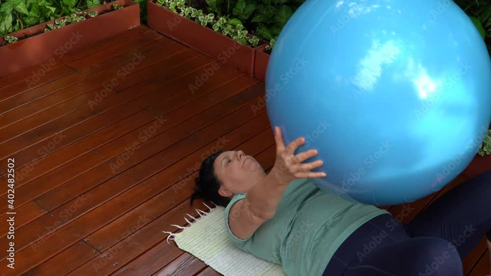 Mujer de mediana edad entrando en el jardín de su casa con ropa deportiva y pelota