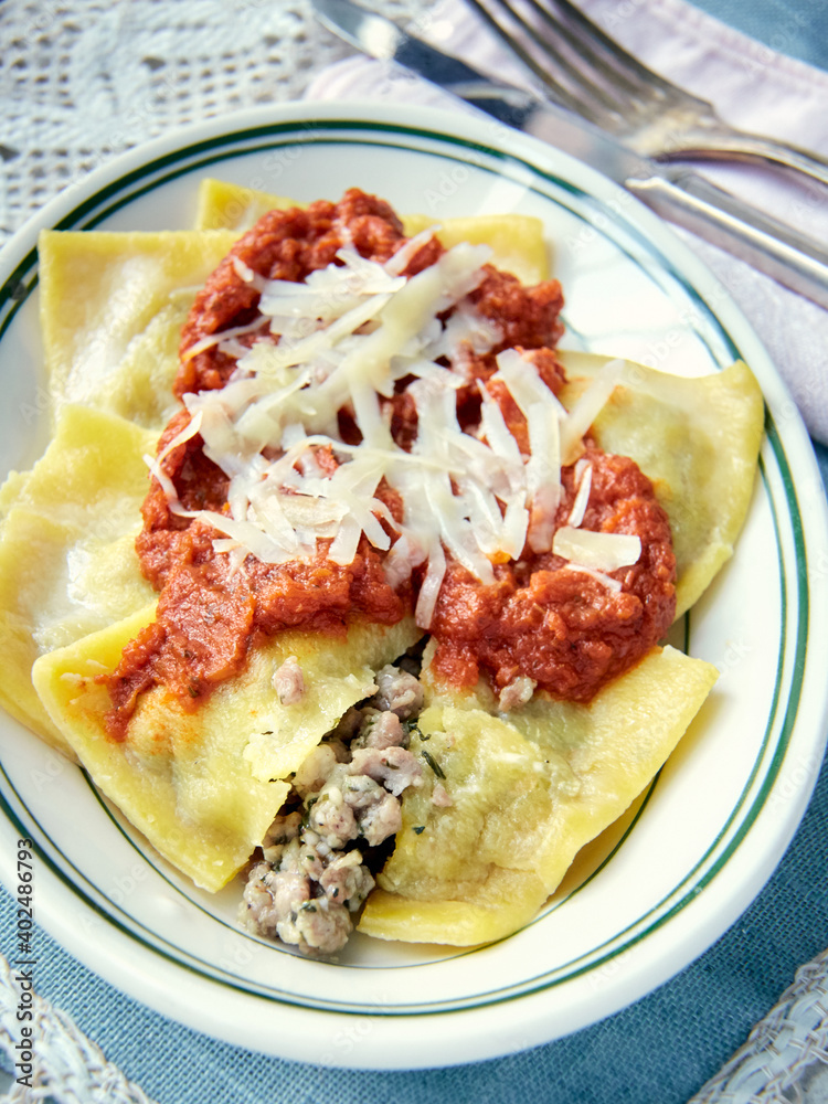 Ravioli with Meat Sauce and Grated Cheese, Wide View on White Plate with Knife and Fork Ravioli with Meat Sauce and Grated Cheese, Wide View on White Plate with Knife and Fork