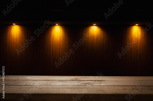 empty wooden table on which beams of light from lamps fall on a dark background  place for your products on the table