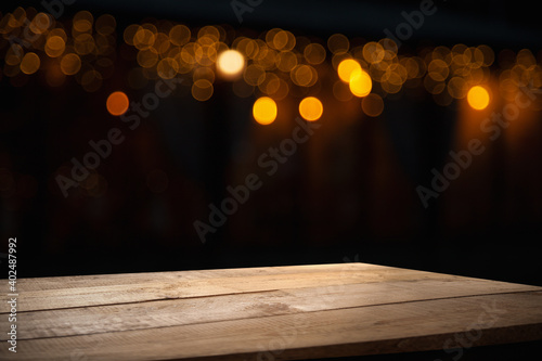 empty wooden table on blurred light gold bokeh of cafe restaurant on dark background, blurred cafe interior place for your products on the table