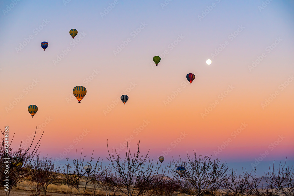 Hot air balloon flying over Cappadocia with full moon, pink sky Hot air balloon flying over Cappadocia with full moon, pink sky