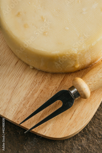 Spanish palmero cheese, on a wooden cheese board with utensils such as fork, knife, all on a stone background. 6 photo