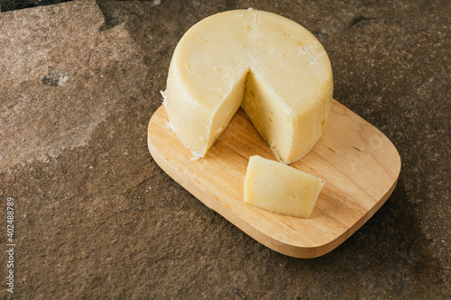 Spanish palmero cheese, on a wooden cheese board with utensils such as fork, knife, all on a stone background. 14 photo