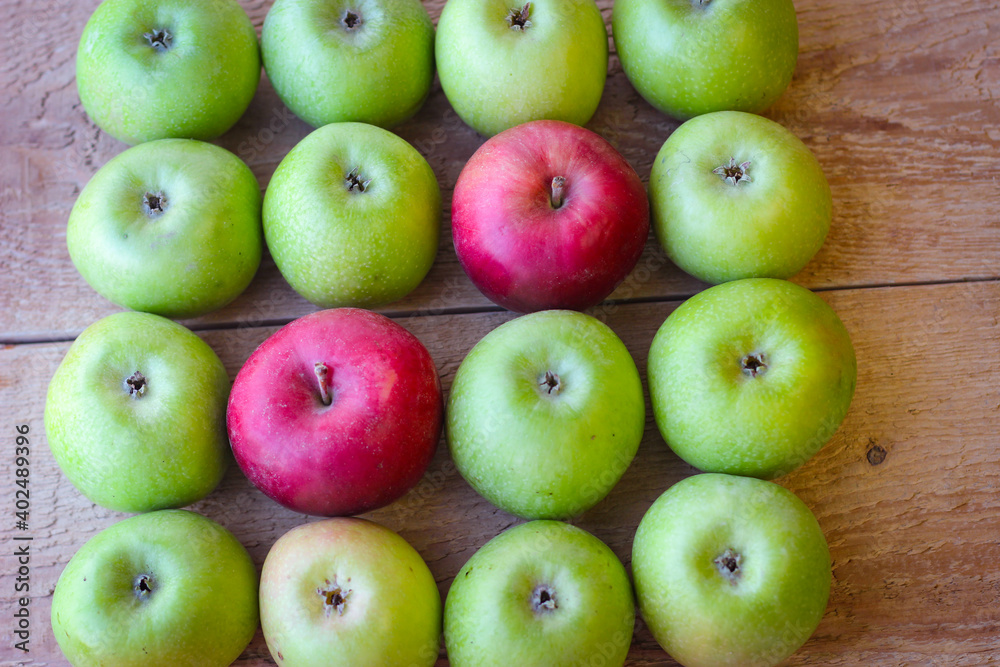 Green and red apples stand on a wooden surface Green and red apples stand on a wooden surface