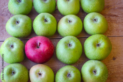 Green and red apples stand on a wooden surface