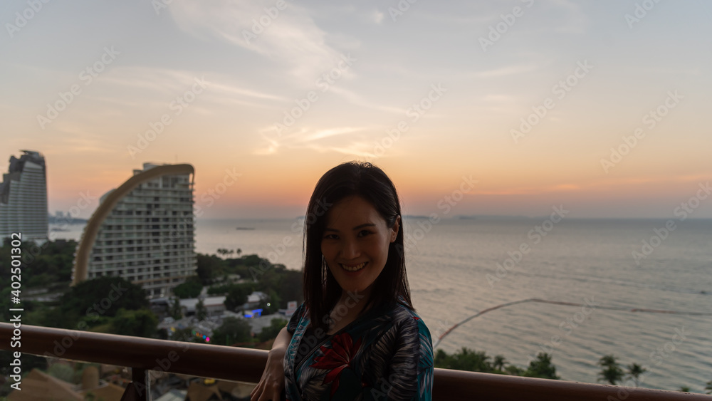 An Asian woman portrait at the hotel with happiness and sunset time in the Pattaya beach, Thailand.