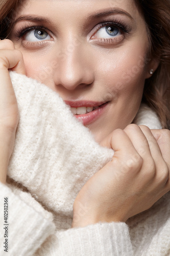 Blonde young beautiful woman dressed in white woolen sweater .