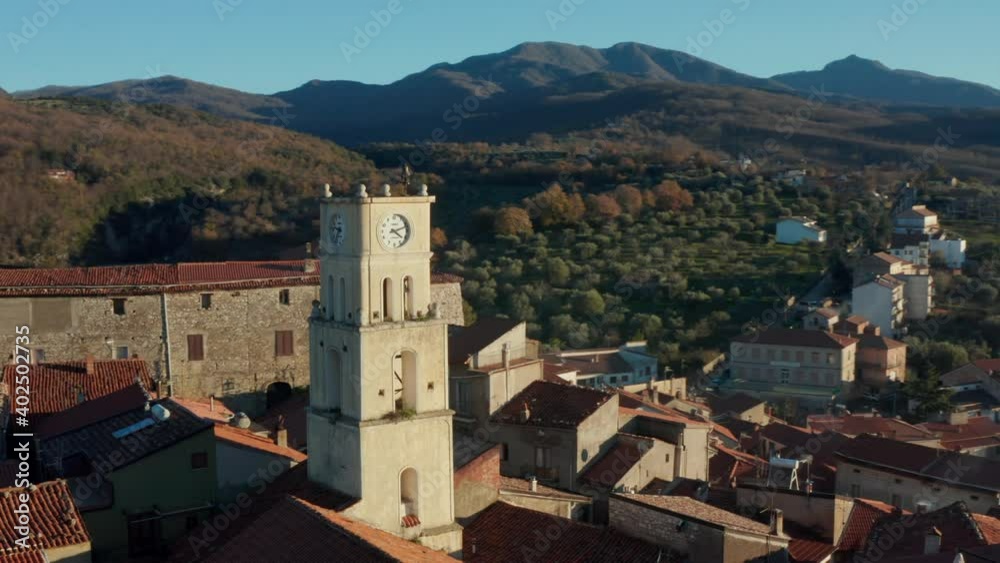 Aerial view around a church bell tower, overlooking homes and houses in a village, sunrise in Campania, Italy - orbit, drone shot Aerial view around a church bell tower, overlooking homes and houses in a village, sunrise in Campania, Italy - orbit, drone shot