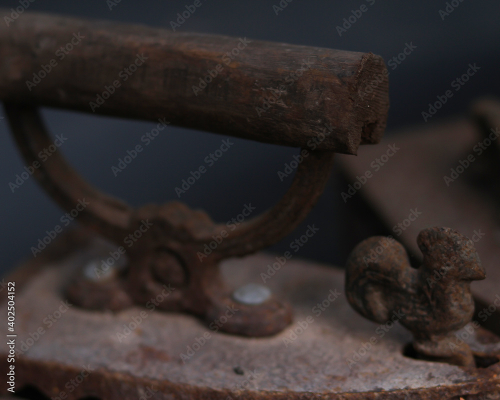 Old rusty antique iron for ironing clothes with the help of charcoal. Household antiques. Iron for clothes made of traditional steel with a wooden handle (Ayam Jago). Detailed photo of an old iron. Old rusty antique iron for ironing clothes with the help of charcoal. Household antiques. Iron for clothes made of traditional steel with a wooden handle (Ayam Jago). Detailed photo of an old iron.