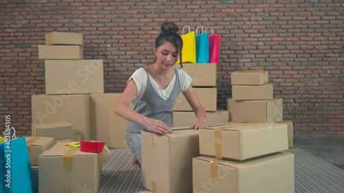 Young Asia entrepreneur businesswoman packing product in cardboard box deliver to customer, working at home office. Small business owner, start up online market delivery, lifestyle freelance concept.