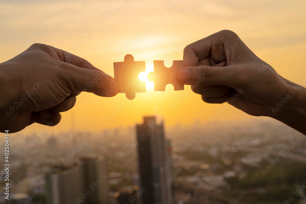 Two hands connect pieces of the puzzle against the sunset. Business concept idea Two hands connect pieces of the puzzle against the sunset. Business concept idea