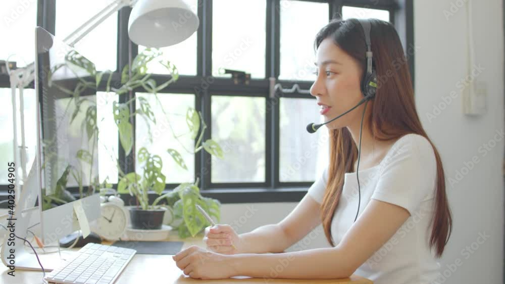 Asian girl student wear wireless headphone study online with skype teacher, happy young woman learn language listen lecture watch webinar write notes look at laptop sit and learn at home Asian girl student wear wireless headphone study online with skype teacher, happy young woman learn language listen lecture watch webinar write notes look at laptop sit and learn at home