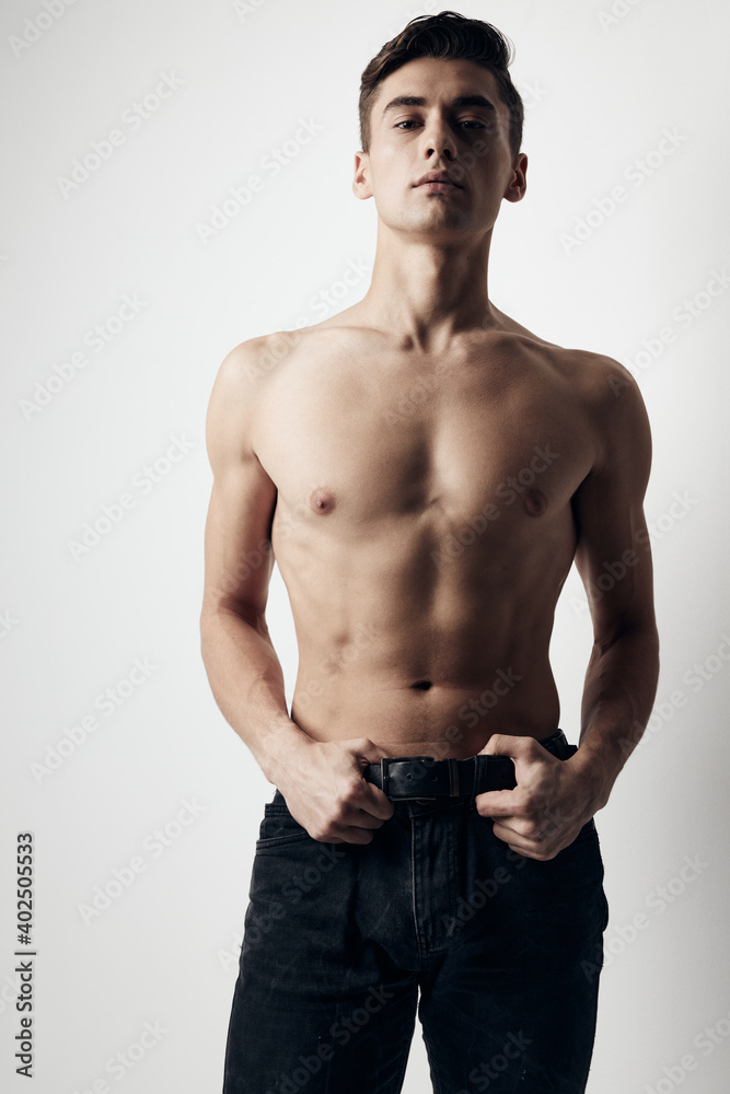 Guy on a light background in trousers naked torso cropped view Guy on a light background in trousers naked torso cropped view