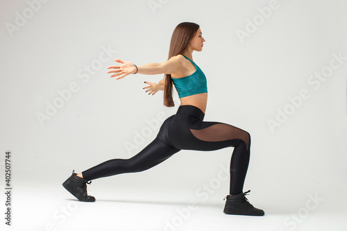 sporty young woman doing stretching lunge exercise isolated on white background