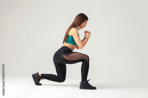 athletic fit sportswoman doing lunge exercise isolated on studio background
