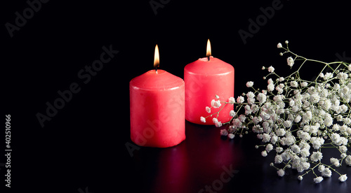 Red burning candles  white flowers on black background. The concept of mourning  sorrow and sadness.