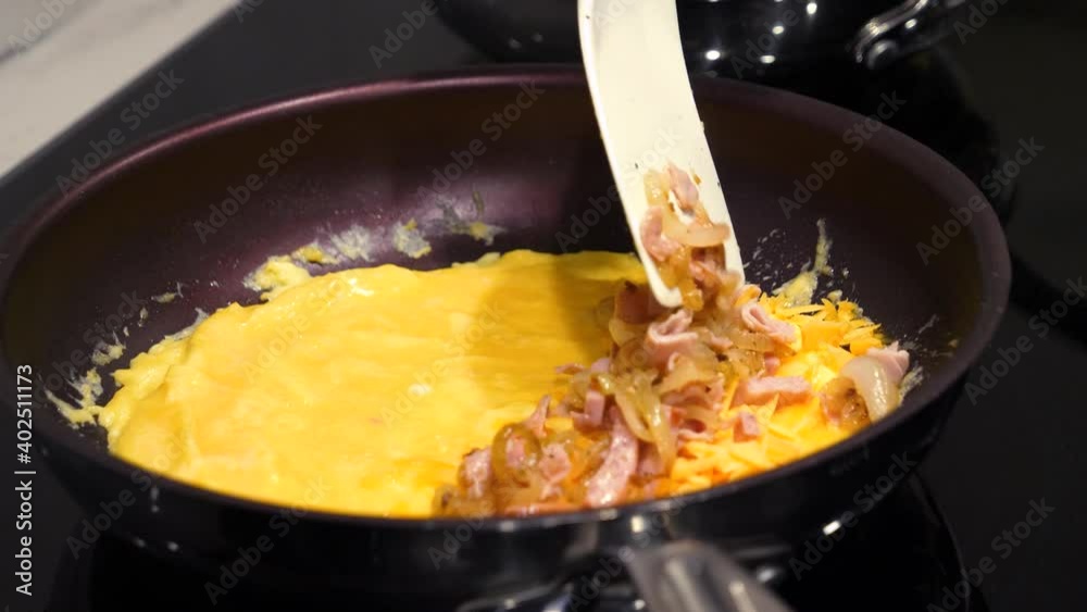 Spatula Adding Cooked Ham and Onions to Egg Omelet - Stovetop Cooking Spatula Adding Cooked Ham and Onions to Egg Omelet - Stovetop Cooking