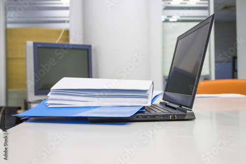 Blue Document folder with documents and Laptop on white table in meeting room