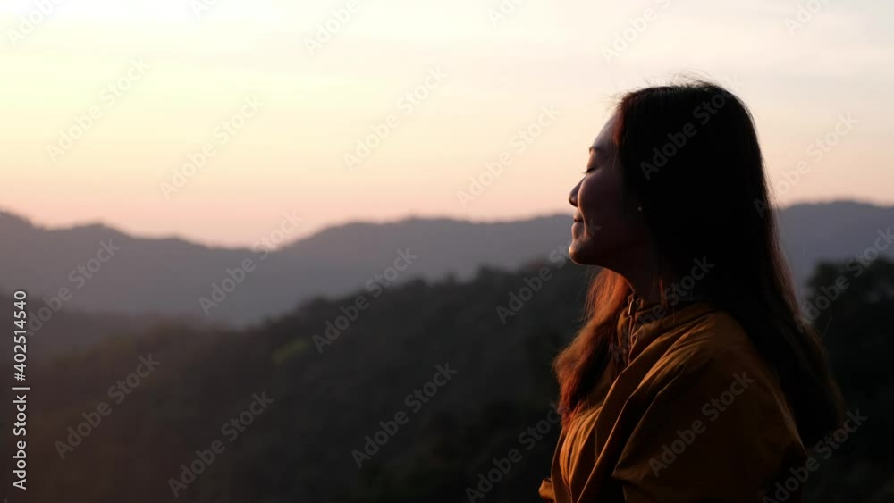 Closeup of a female traveler sitting on the mountain peak and watching sunrise in the morning Closeup of a female traveler sitting on the mountain peak and watching sunrise in the morning
