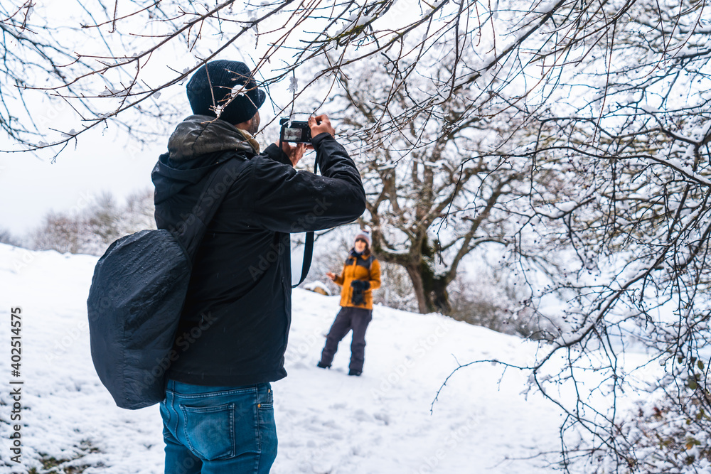 A young man photographing a girl in the snow. Snow in the town of Opakua near Vitoria in Araba, Basque Country. Spain