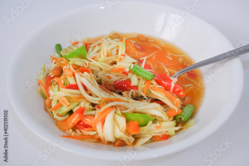 Thai papaya salad (som tum) with a spoon and white plate