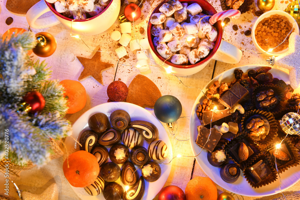 sweet food top view background for merry christmas or new year holiday decoration with night illumination - chocolate candies, tangerines, cookies, marshmallow and cocoa latte on white wood sweet food top view background for merry christmas or new year holiday decoration with night illumination - chocolate candies, tangerines, cookies, marshmallow and cocoa latte on white wood