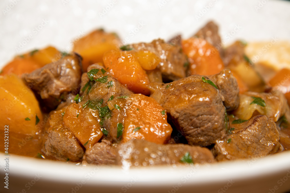 A delicious plate of Venison Stew with root vegetables on a wooden kitchen work top A delicious plate of Venison Stew with root vegetables on a wooden kitchen work top