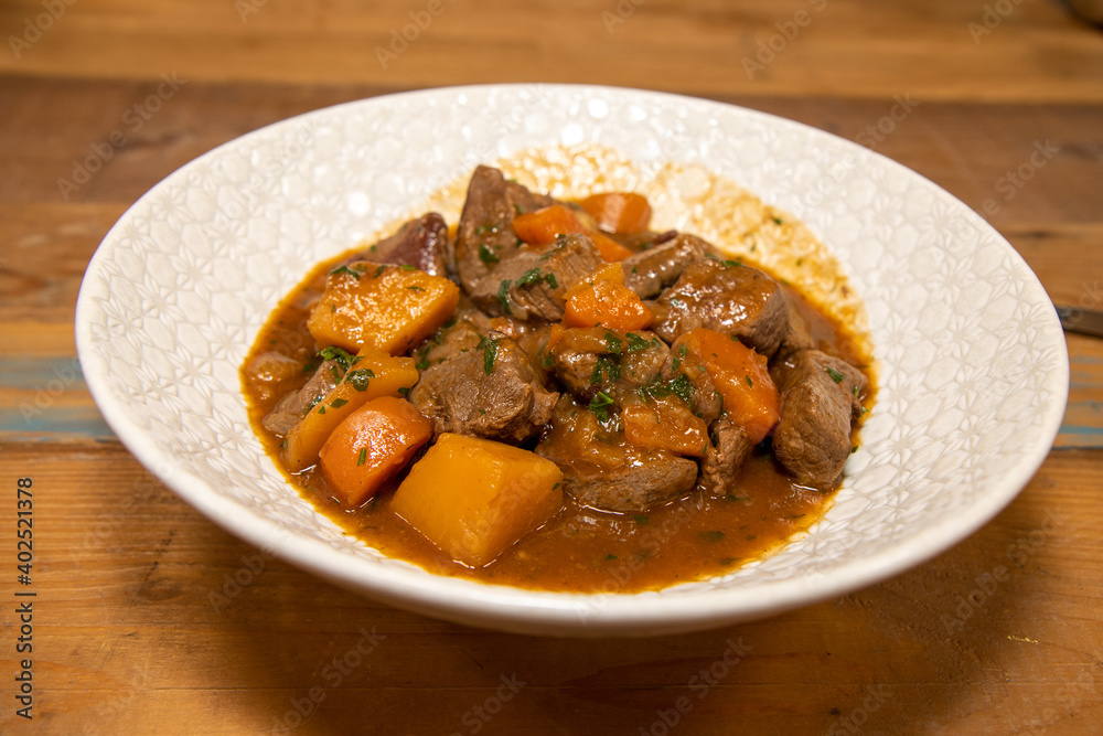 A delicious plate of Venison Stew with root vegetables on a wooden kitchen work top A delicious plate of Venison Stew with root vegetables on a wooden kitchen work top