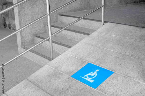 Blue disabled sign for wheelchair lane beside concrete stair 