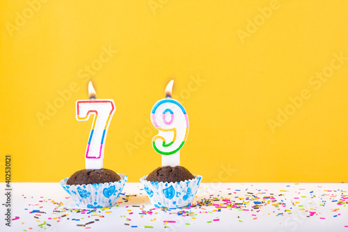 79 number candle on a cup cake with colorful sprinkles and yellow background seventy ninth birthday anniversary celebrations photo