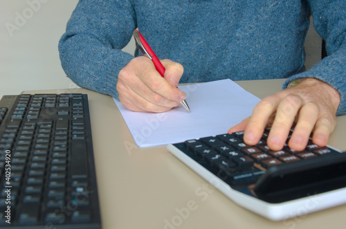 Wallpaper Mural Man in blue sweater writing with pocket calculator Torontodigital.ca