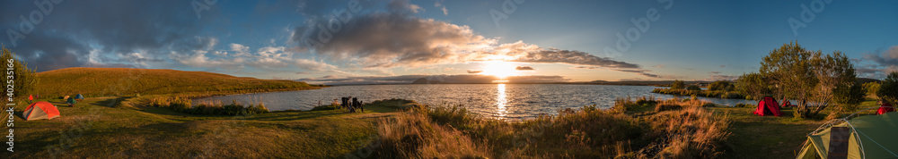 Panoramic view of lake Myvatn in Highlands of Iceland with camping tents at campsite during amazing sunset in summer, Iceland.
