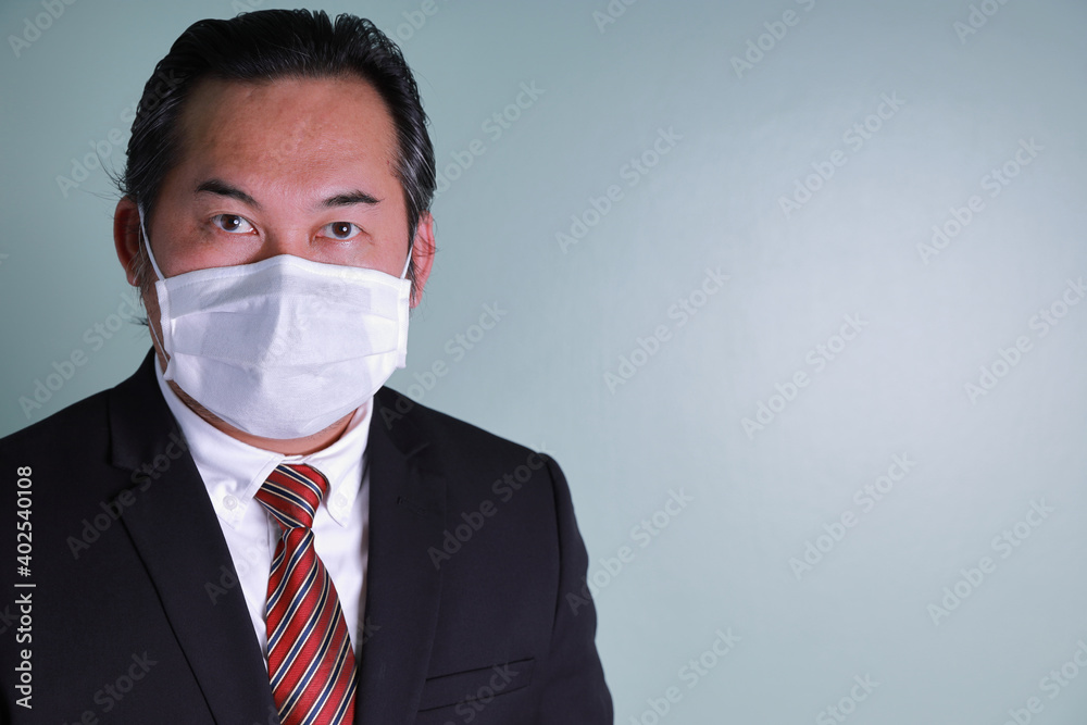Close up portrait of Asian businessman wearing a medical mask looking at camera with copy space. Concept businesspeople health care for protect pandemic flu coronavirus. Close up portrait of Asian businessman wearing a medical mask looking at camera with copy space. Concept businesspeople health care for protect pandemic flu coronavirus.