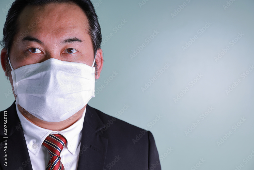 Close up portrait of Asian businessman wearing a medical mask looking at camera with copy space. Concept businesspeople health care for protect pandemic flu coronavirus. Close up portrait of Asian businessman wearing a medical mask looking at camera with copy space. Concept businesspeople health care for protect pandemic flu coronavirus.