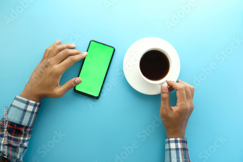 top view of man hand using smart phone and drinking tea 
