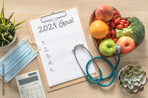 2021 New Year Goals in new normal lifestyle, work-life balance with face mask safety awareness from covid-19, healthy food, good heart health, blank resolution list on white paper medical clipboard