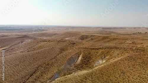 Long straight flight over the hills in the Negev desert in Israel with road traffic in the distant background