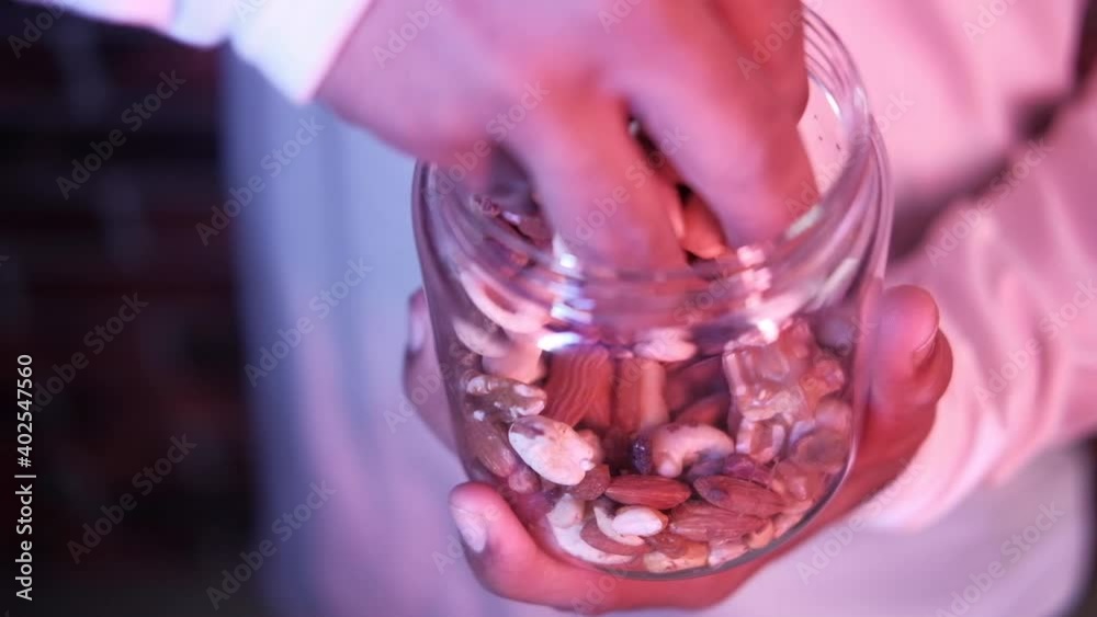 young man picking mixed nut from a bowl young man picking mixed nut from a bowl