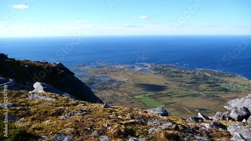 Beautiful panoramic view over the northern coast of Lofoten islands, Norway with village Straumnes on the blue Norwegian Sea and rocky meadow in front with blades of grass in the wind. photo