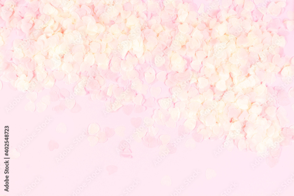 Holiday romantic gentle abstract background for the design. Pink confetti in shape of hearts on pastel background. Top view, flat lay composition. Copy space for text.
