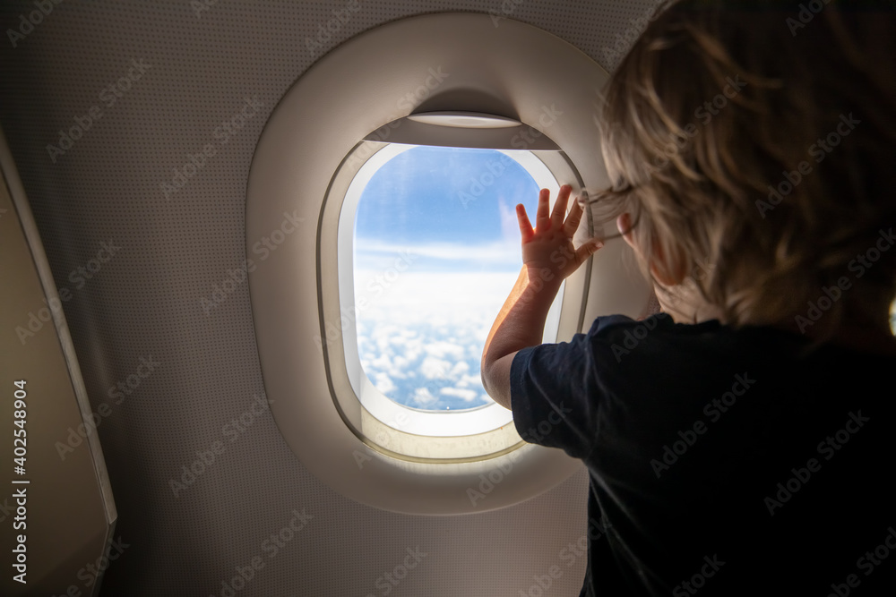 cute toddler points his finger at the sky through the window. first flight concept, traveling with children. - obrazy, fototapety, plakaty 
