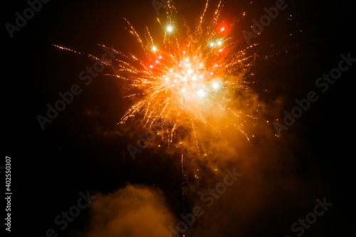 Bright colorful New Year's fireworks in the field in the village. Multi-colored fireworks lights. Flash in the village. Belarus. December 2020.