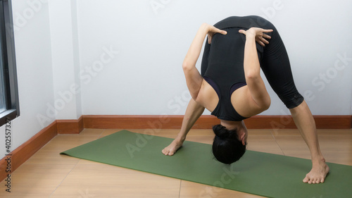 Asian young woman wear a black yoga outfit . Practicing yoga Standing Asanas Action PRASARITA PADOTTANASANA B .Home yoga practice on white background